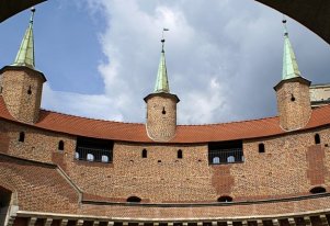 Kolorowa fotografia. Budynek Barbakanu z widocznymi murami i wieżyczkami.