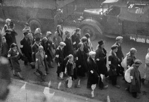 Czarno-biała fotografia przedstawiająca ludzi idących ulicą