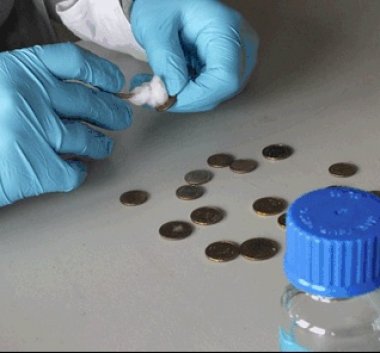 Zdjęcie z warsztatów. Osoba czyszcząca monety w rękawiczkach.