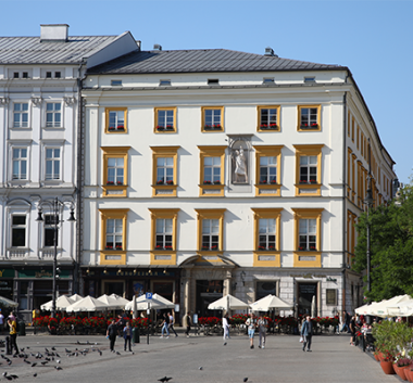 Kolorowa fotografia. Budynek Pałacu Krzysztofory w letniej scenerii Rynku Głównego.