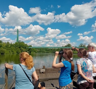 Kolorowa fotografia. Osoby na łodzi obserwujące przyrodę.