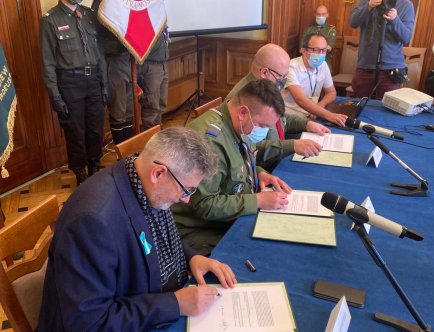 Trzej mężczyzn podpisujących dokument.