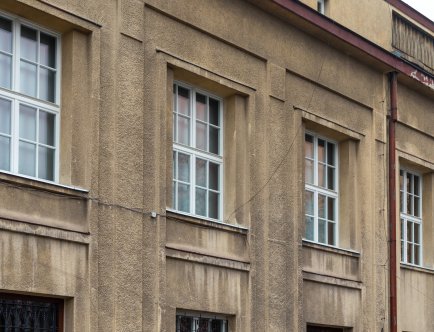 Kolorowa fotografia. Elewacja zabytkowego budynku z widocznymi oknami i drzwiami.