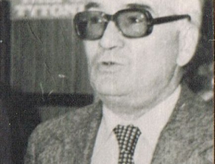 Na zdjęciu przedstawiony jest elegancko ubrany mężczyzna w średnim wieku w okularach.