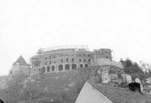 Fotografia czarnobiała. Na wzgórzu zamek w czasie budowy, z nie dokończonym dachem